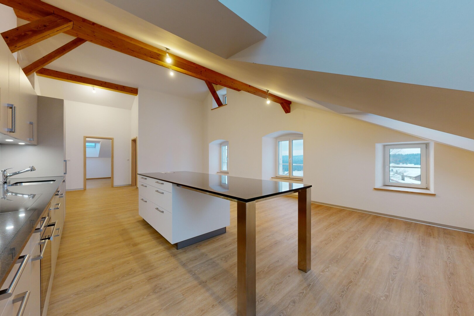 cuisine avec plancher de bois, poutres apparentes, plan de travail, plafond voûté, et lumière naturelle