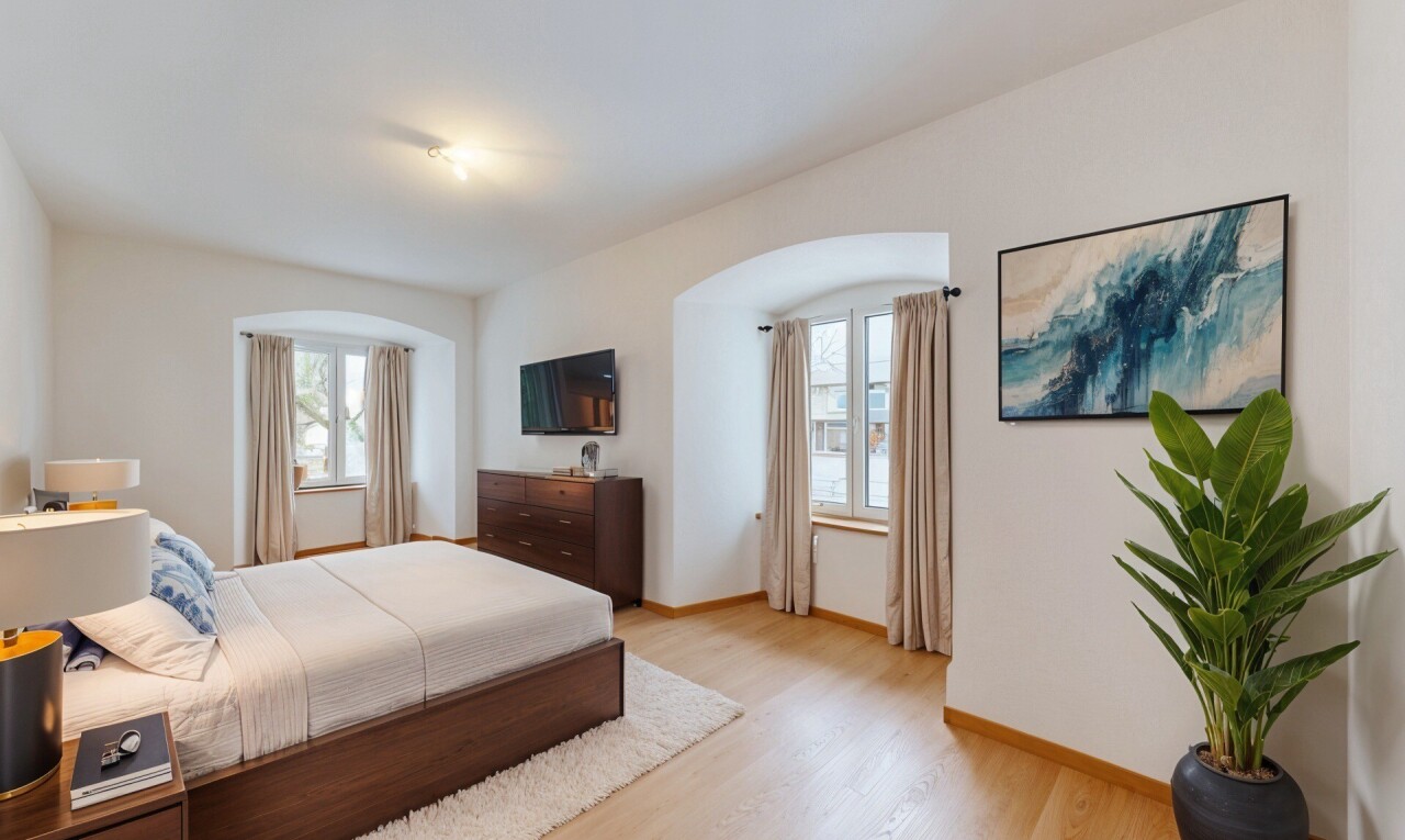 chambre avec cloison sèche, télévision, lumière naturelle, et sol en finition bois