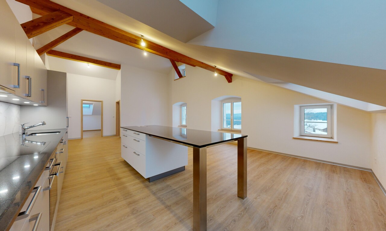 cuisine avec plancher de bois, poutres apparentes, plan de travail, plafond voûté, et lumière naturelle