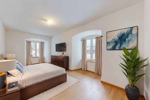 chambre avec cloison sèche, télévision, lumière naturelle, et sol en finition bois