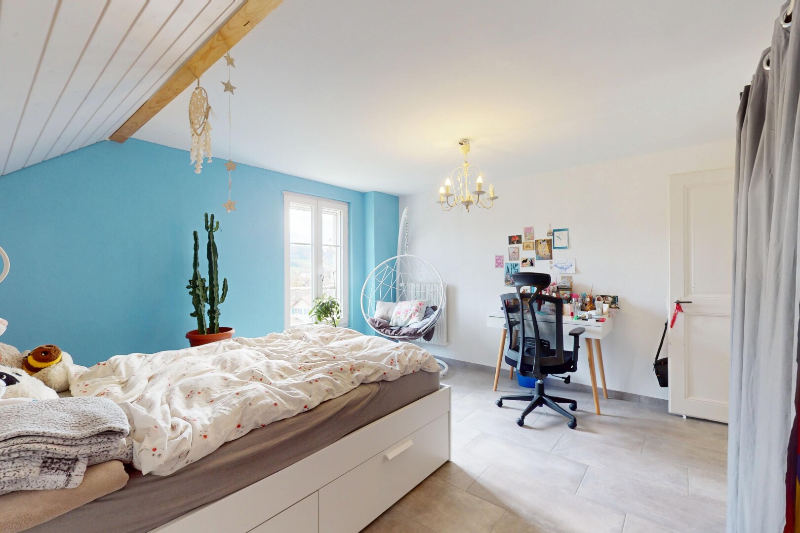 chambre avec plafond à poutres, lumière naturelle, espace bureau, lustre remarquable, et cloison sèche