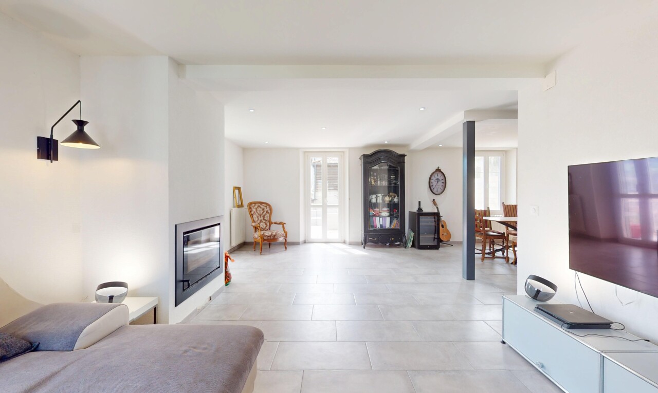 salon avec cheminée, lumière naturelle, sol en carrelage, cloison sèche, et télévision