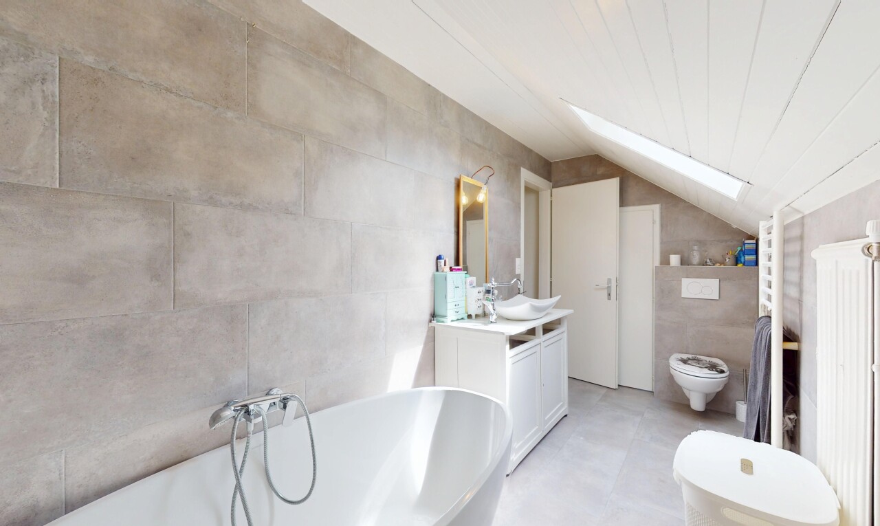salle de bains avec salle de bain complète, bain, plafond voûté, miroir, et toilette