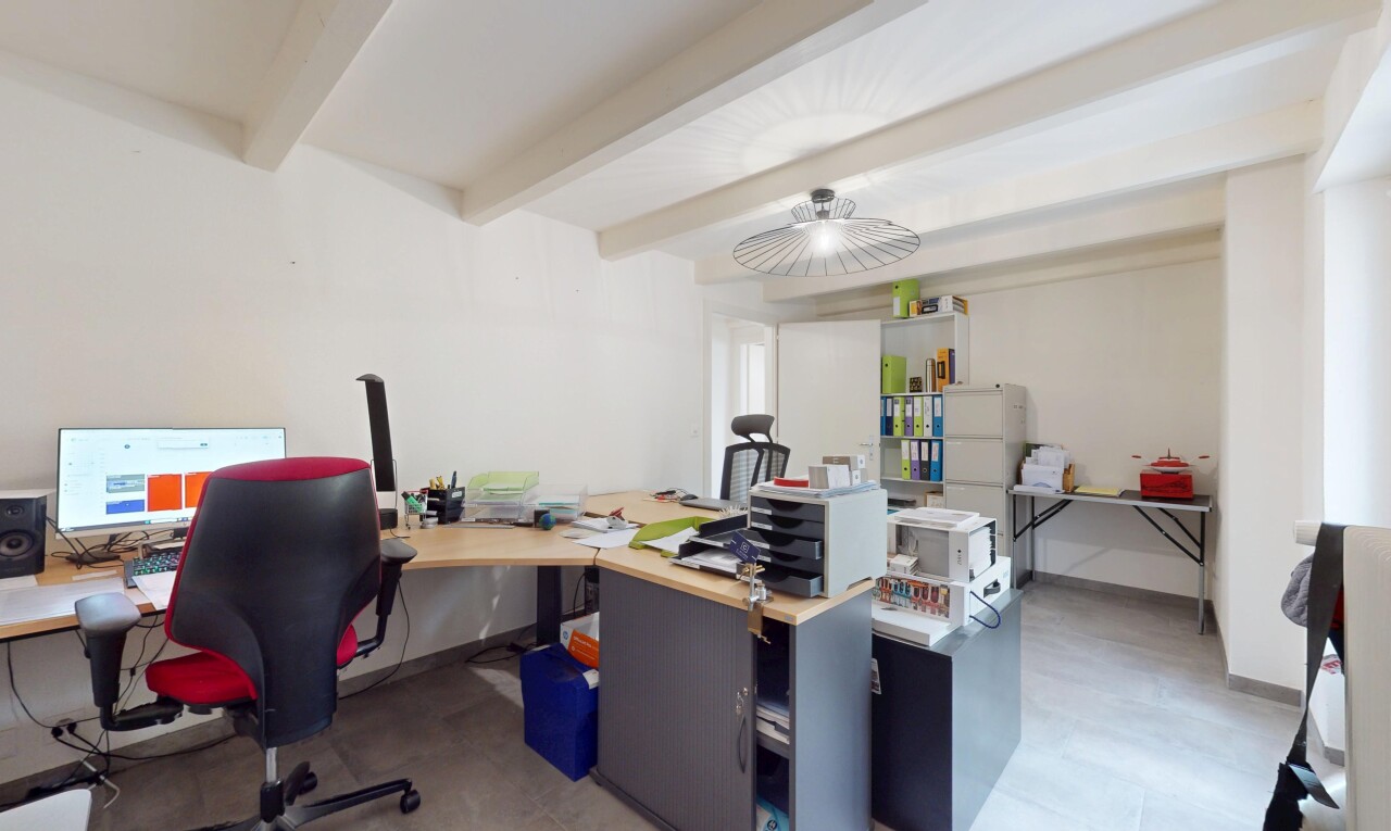 bureau avec télévision, espace bureau, plafond à poutres, et cloison sèche