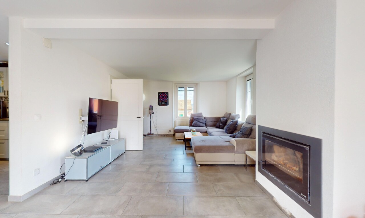 salon avec télévision, lumière naturelle, plafond à poutres, et cloison sèche