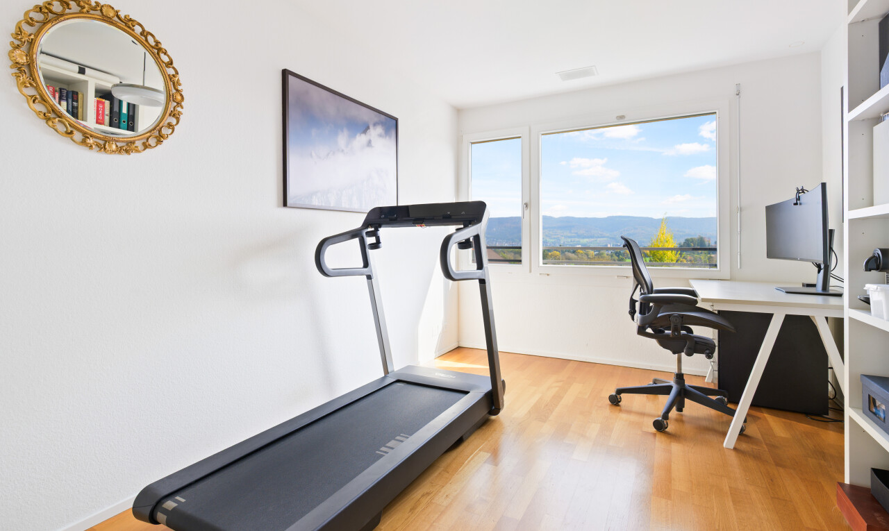 fitnessstudio mit wood finish floor, holzfußboden, inside property, fernseher, und natural light