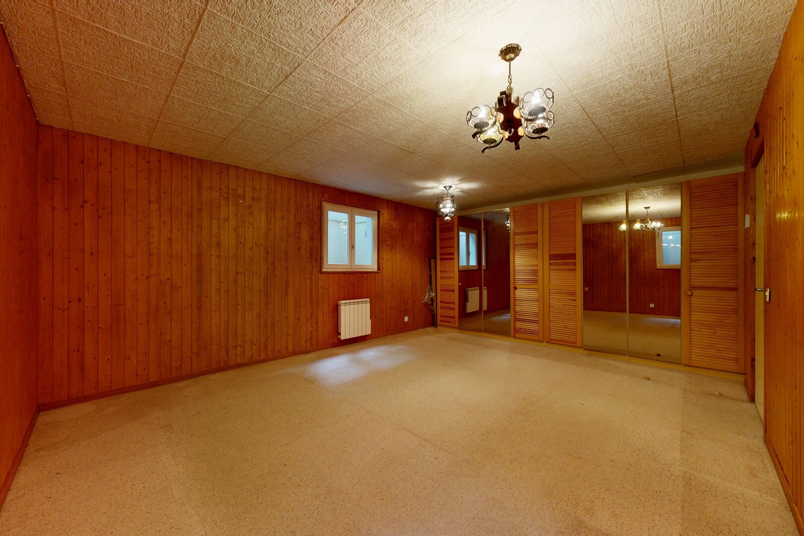 leerer raum mit inside property, bemerkenswerter kronleuchter, holzwand, wood wall, und teppich