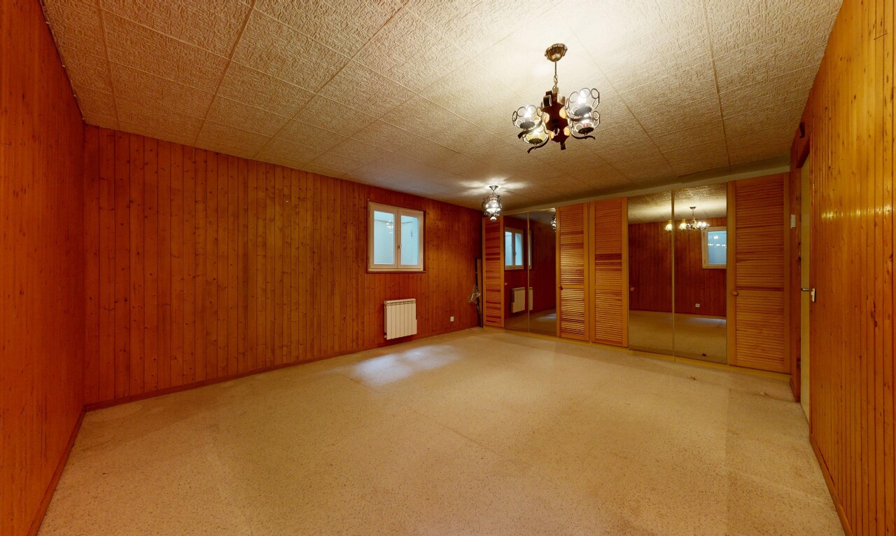 leerer raum mit inside property, bemerkenswerter kronleuchter, holzwand, wood wall, und teppich