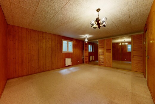 leerer raum mit inside property, bemerkenswerter kronleuchter, holzwand, wood wall, und teppich