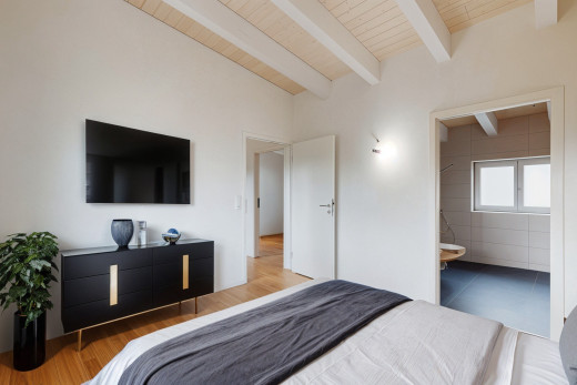 zimmer / schlafzimmer mit parkettboden, balkendecke, holzdecke, fernseher, und natürliches licht