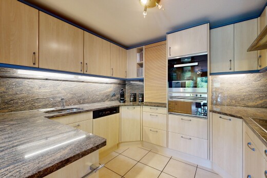 küche mit dark countertops, hellbraune schränke, light brown cabinets, light floor, und küchenrückwand beim Herd