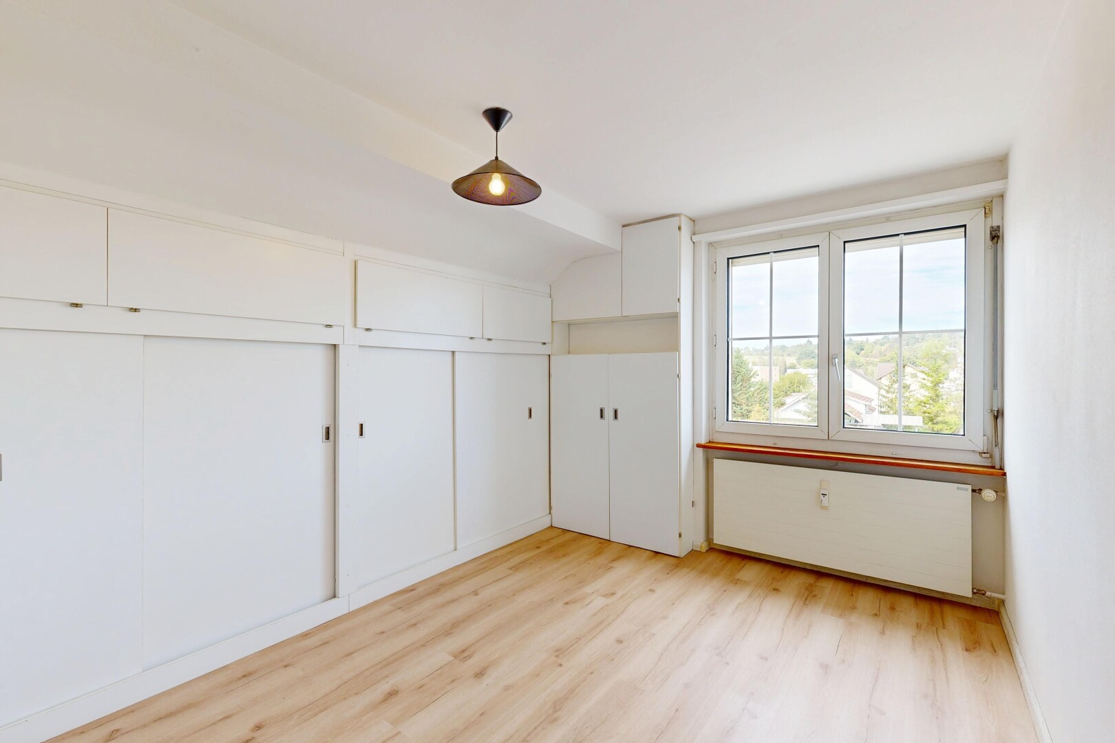 empty room featuring light wood-style flooring and hanging light fixtures