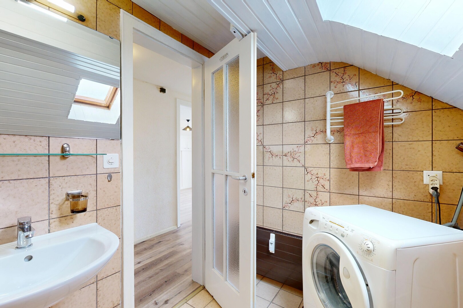 bathroom with tile walls, washer / dryer, and lofted ceiling with skylight