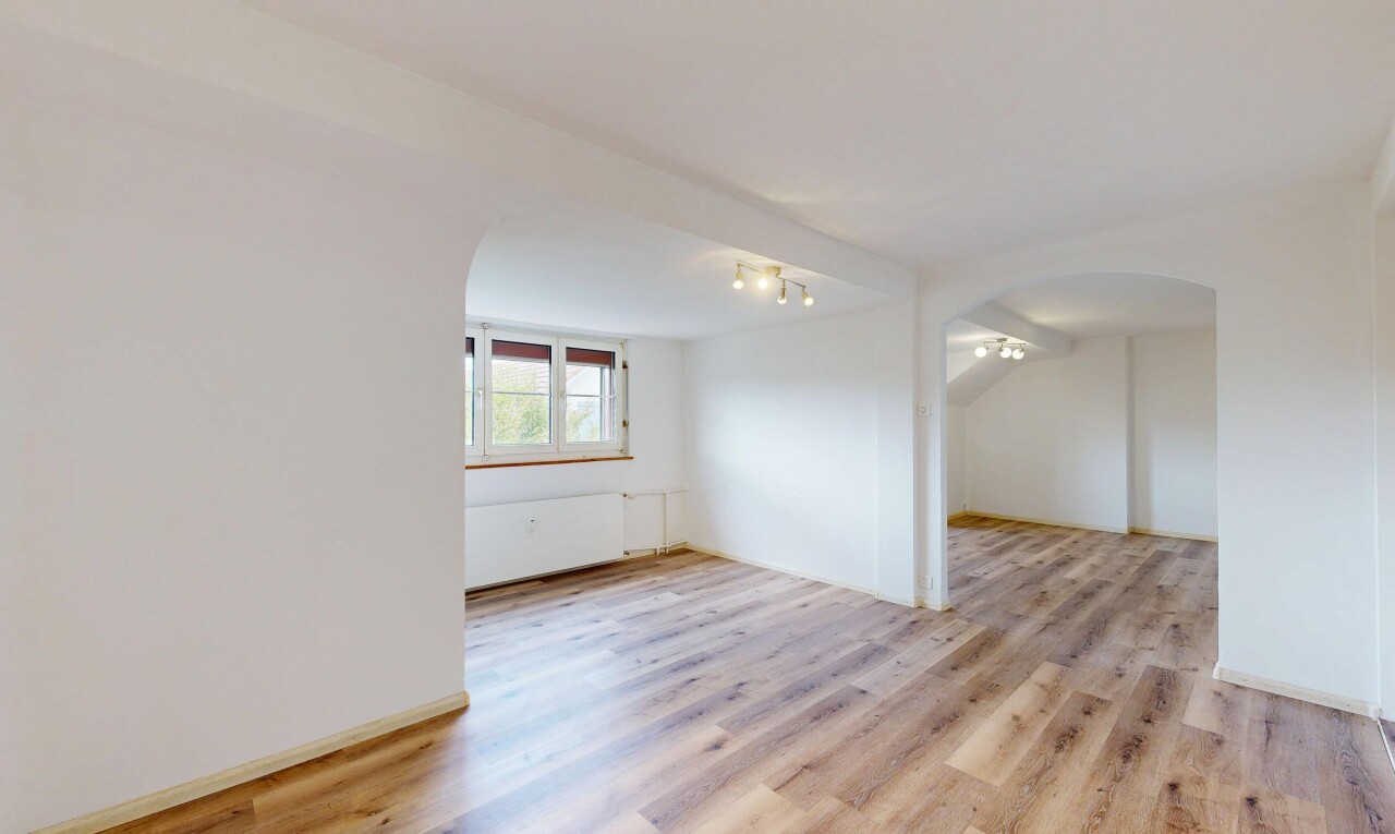 unfurnished room with track lighting, arched walkways, and light wood-style floors