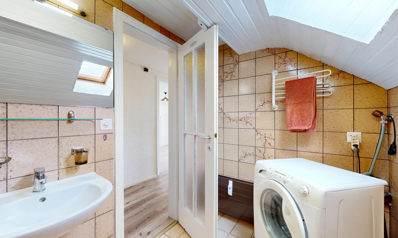 bathroom with tile walls, washer / dryer, and lofted ceiling with skylight