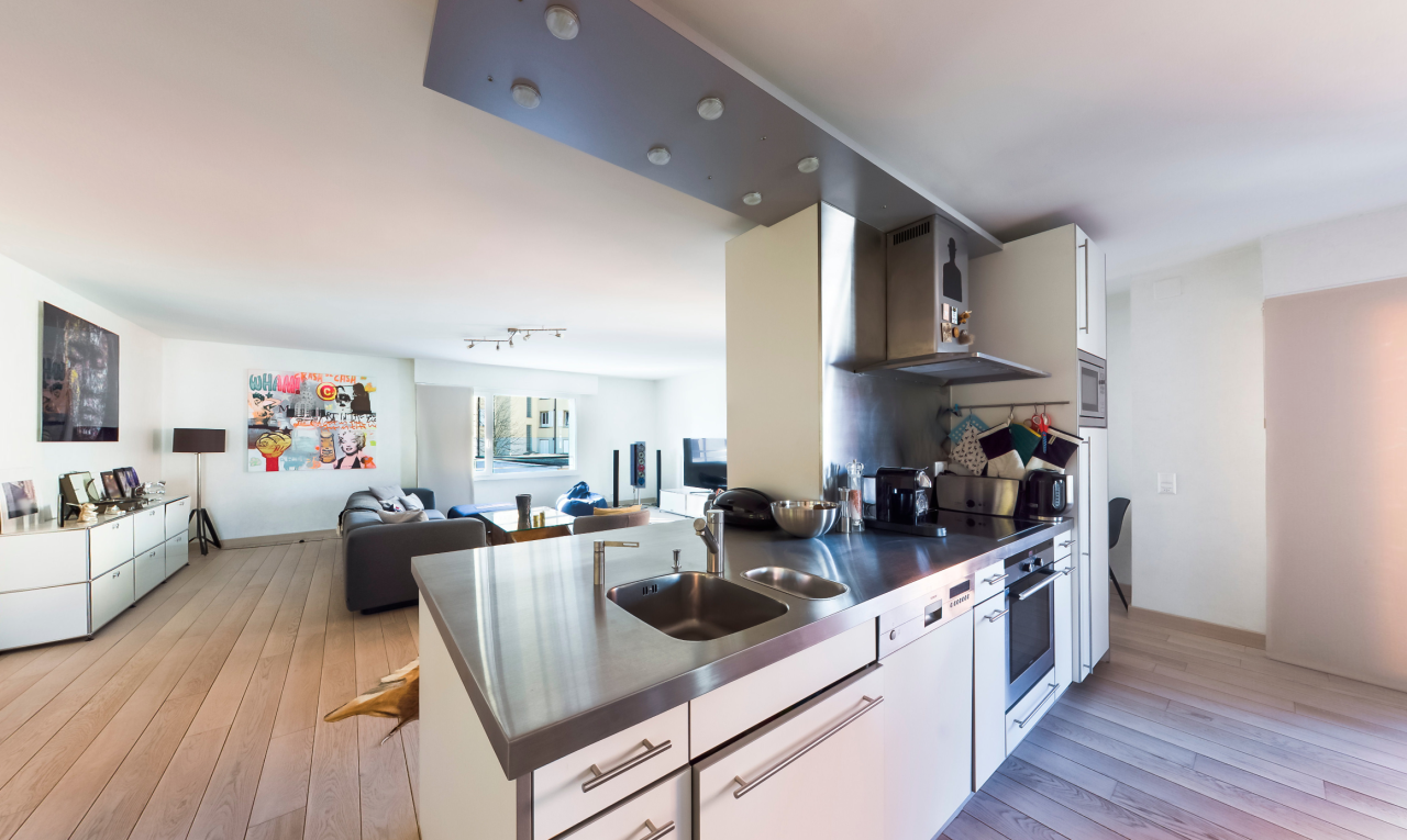 cuisine avec stainless steel countertops, plans de travail en acier inoxydable, opens to living area, ouvert sur l'espace de vie, et light floor