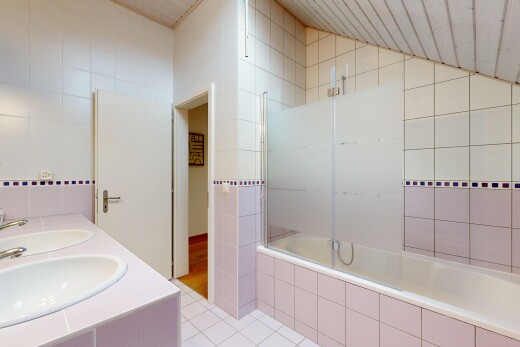 bathroom with tile walls, tiled shower / bath, light tile patterned floors, and double vanity