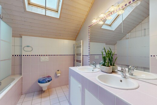 full bath featuring a skylight, tile walls, double vanity, a vaulted wooden ceiling, and light tile patterned flooring