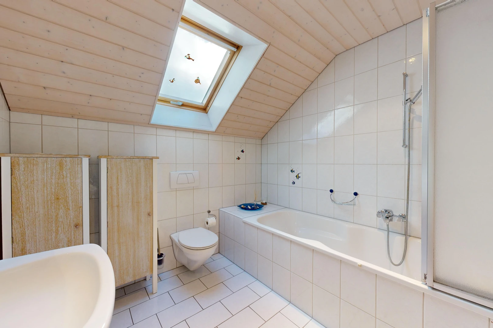 salle de bains avec plafond voûté, carrelage, mur carrelé, et lucarne