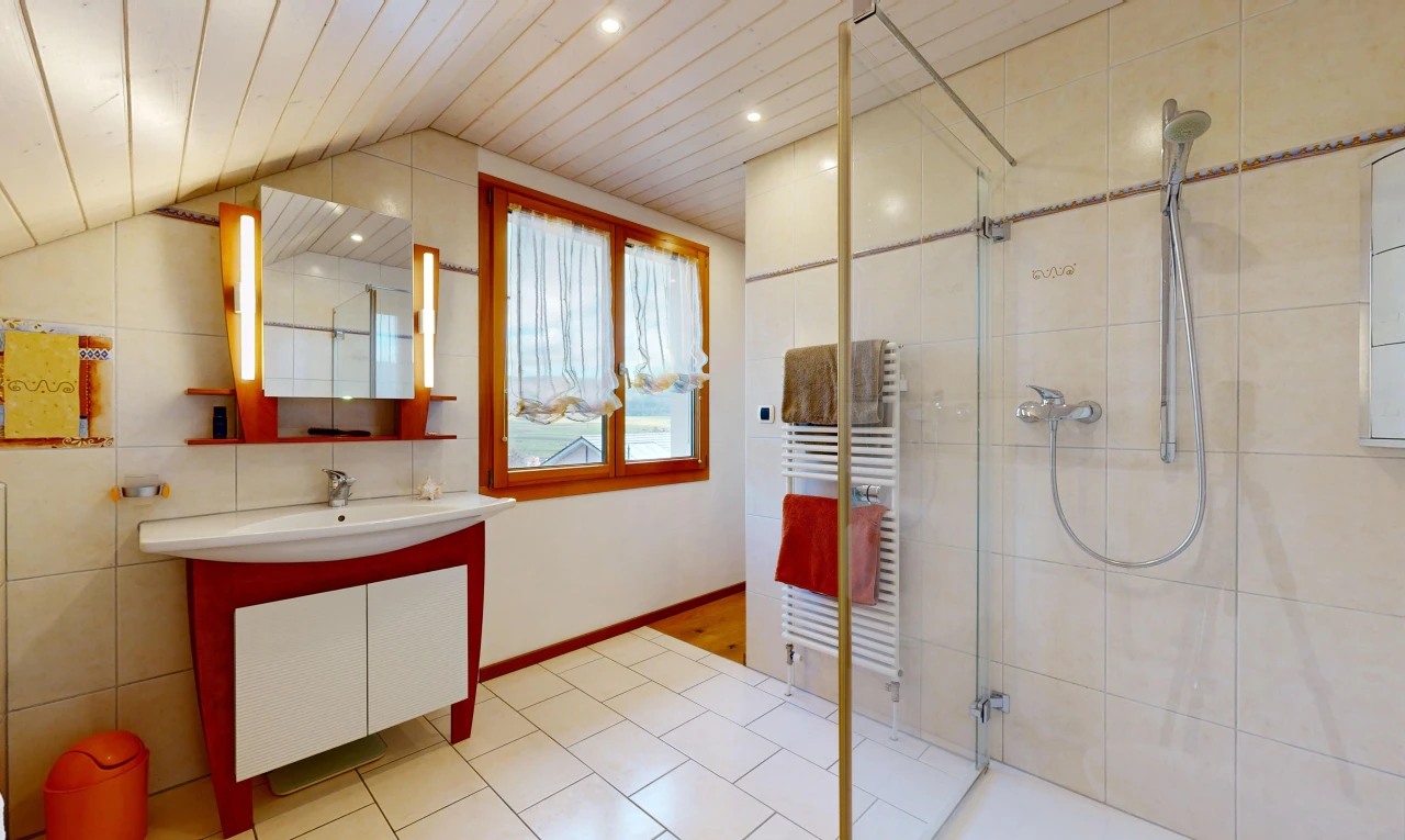 salle de bains avec radiateur, plafond voûté, meuble-lavabo, lumière naturelle, et miroir