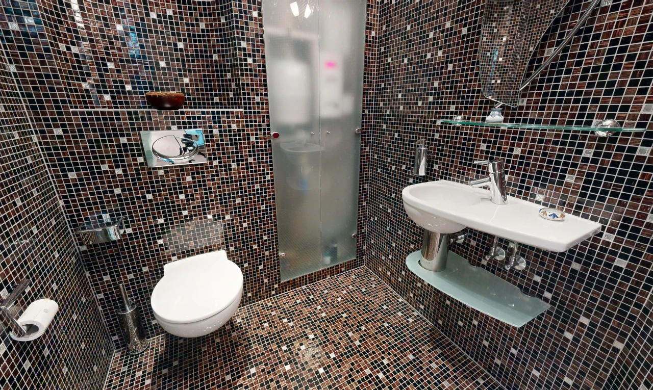 salle de bains avec mur carrelé, toilettes, et carrelage