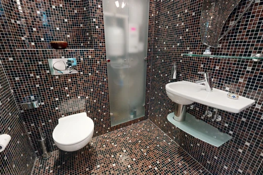 salle de bains avec mur carrelé, toilettes, et carrelage