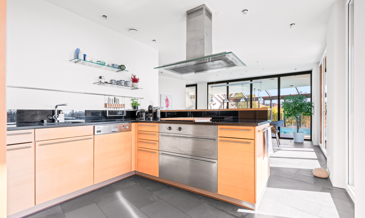 cuisine avec plans de travail, dark countertops, armoires marron clair, light brown cabinets, et péninsule de cuisine