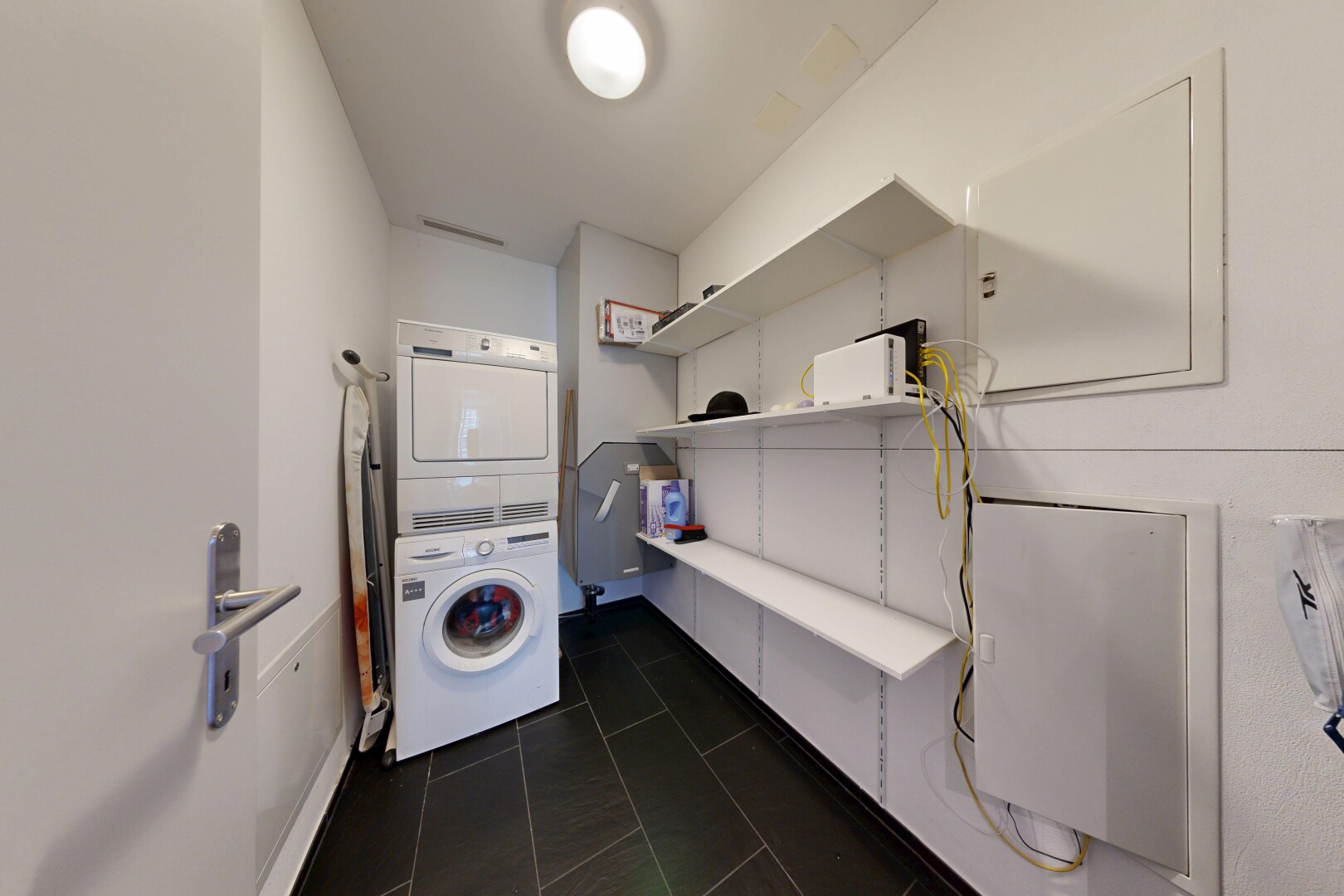 buanderie avec lave-linge et sèche-linge superposés, dark floor, cloison sèche, drywall, et inside property