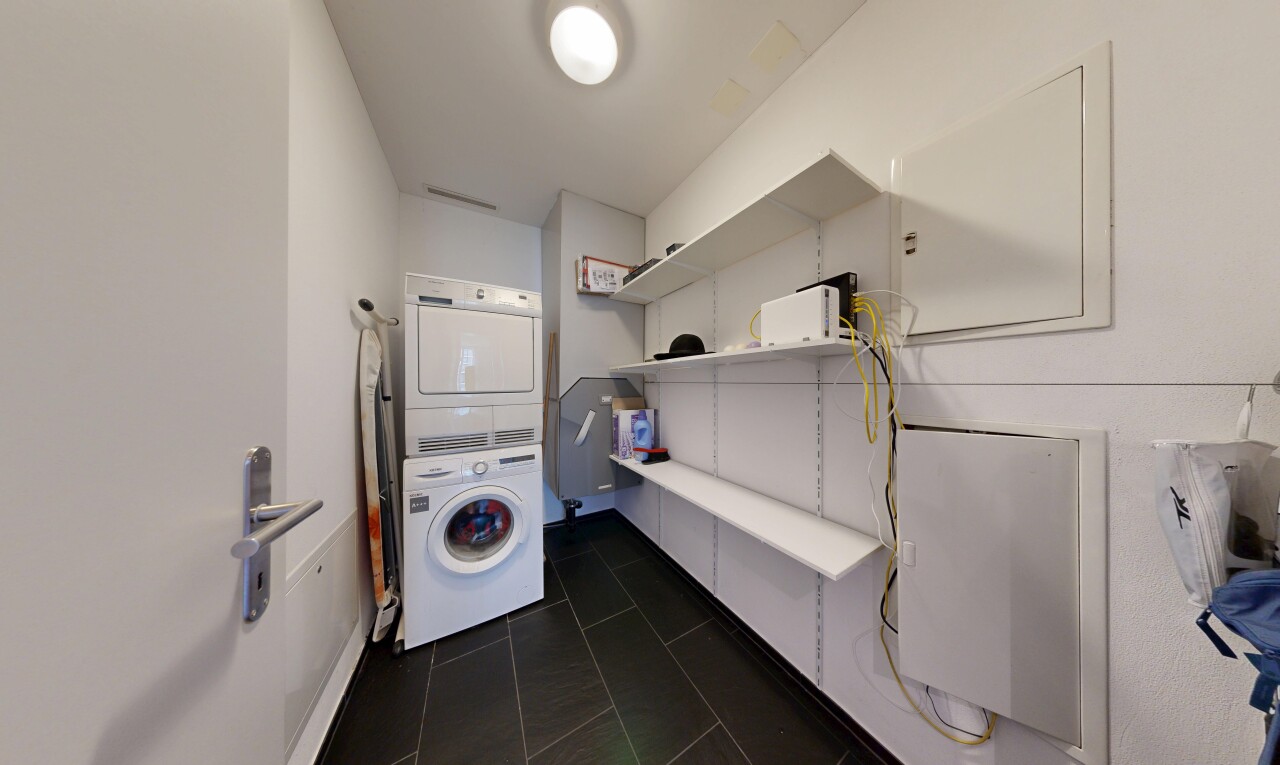 buanderie avec lave-linge et sèche-linge superposés, dark floor, cloison sèche, drywall, et inside property