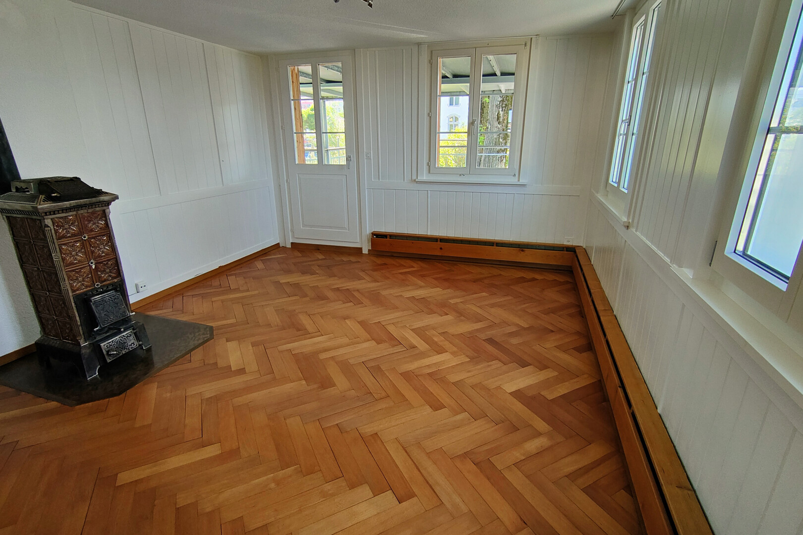 pièce vide avec parquet floor, radiateur à plinthe, wood finish floor, sol en finition bois, et paneling wall