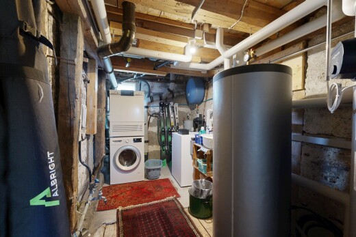 buanderie avec buanderie, chauffe-eau, sous-sol, lave-linge et sèche-linge superposés, et inside property