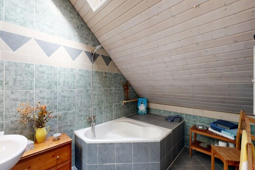 full bathroom with tile walls, vaulted ceiling, a garden tub, vanity, and dark tile patterned floors