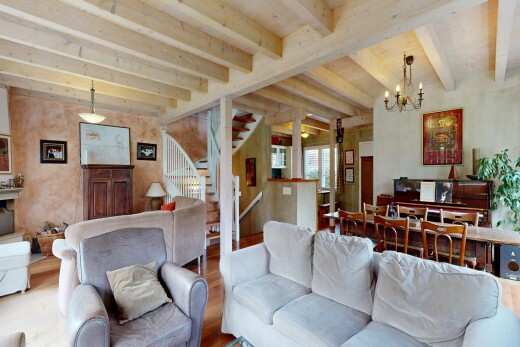 living room featuring suspended lighting, beam ceiling, and wood finished floors