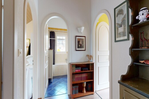 hallway with arched walkways and light tile patterned floors