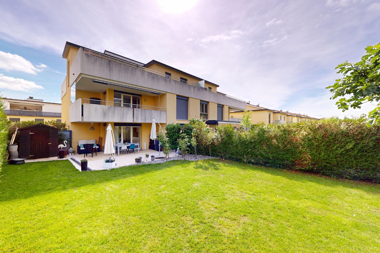 view of property featuring a balcony, a patio area, a lawn, and stucco siding