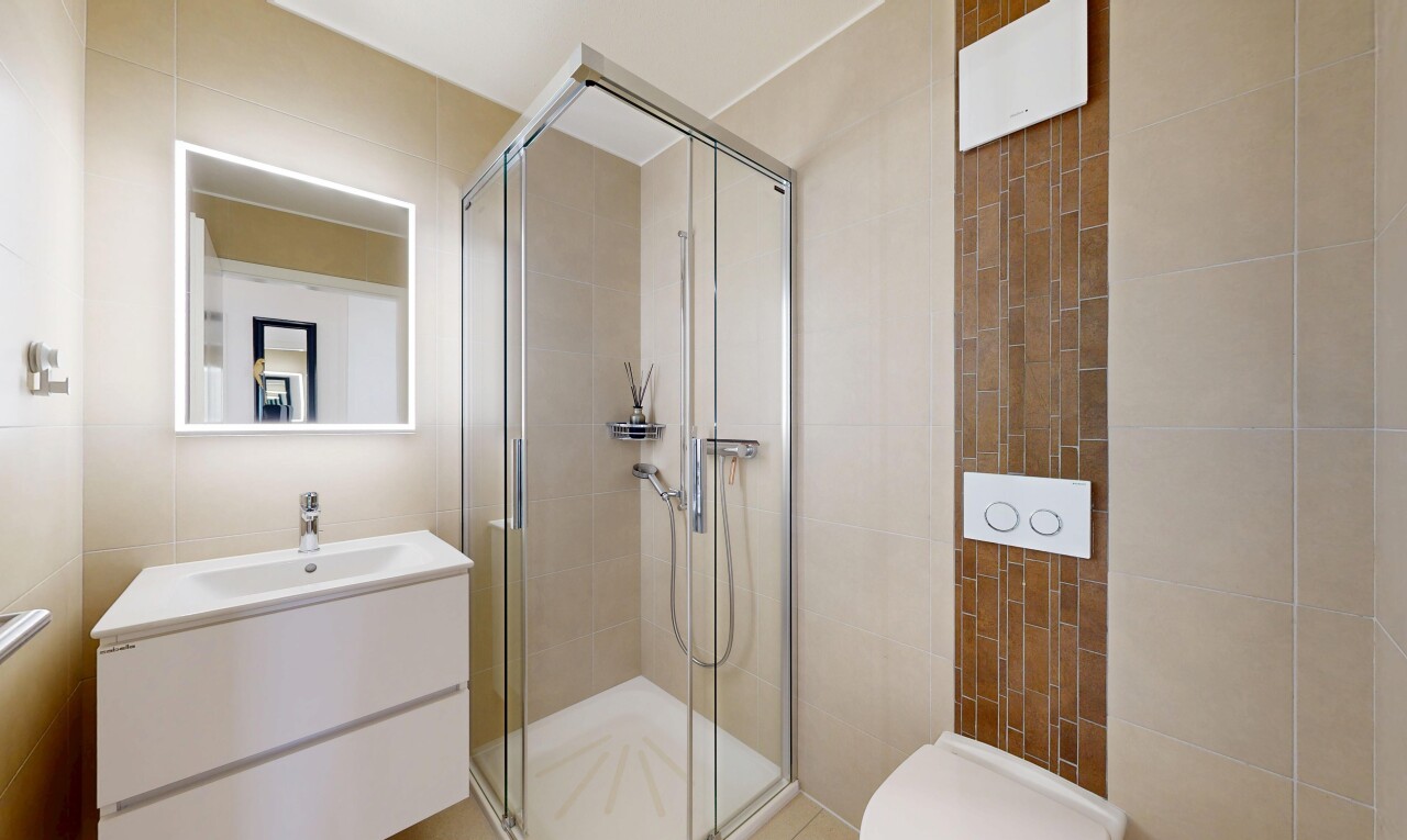bathroom with a shower stall, vanity, and tile walls