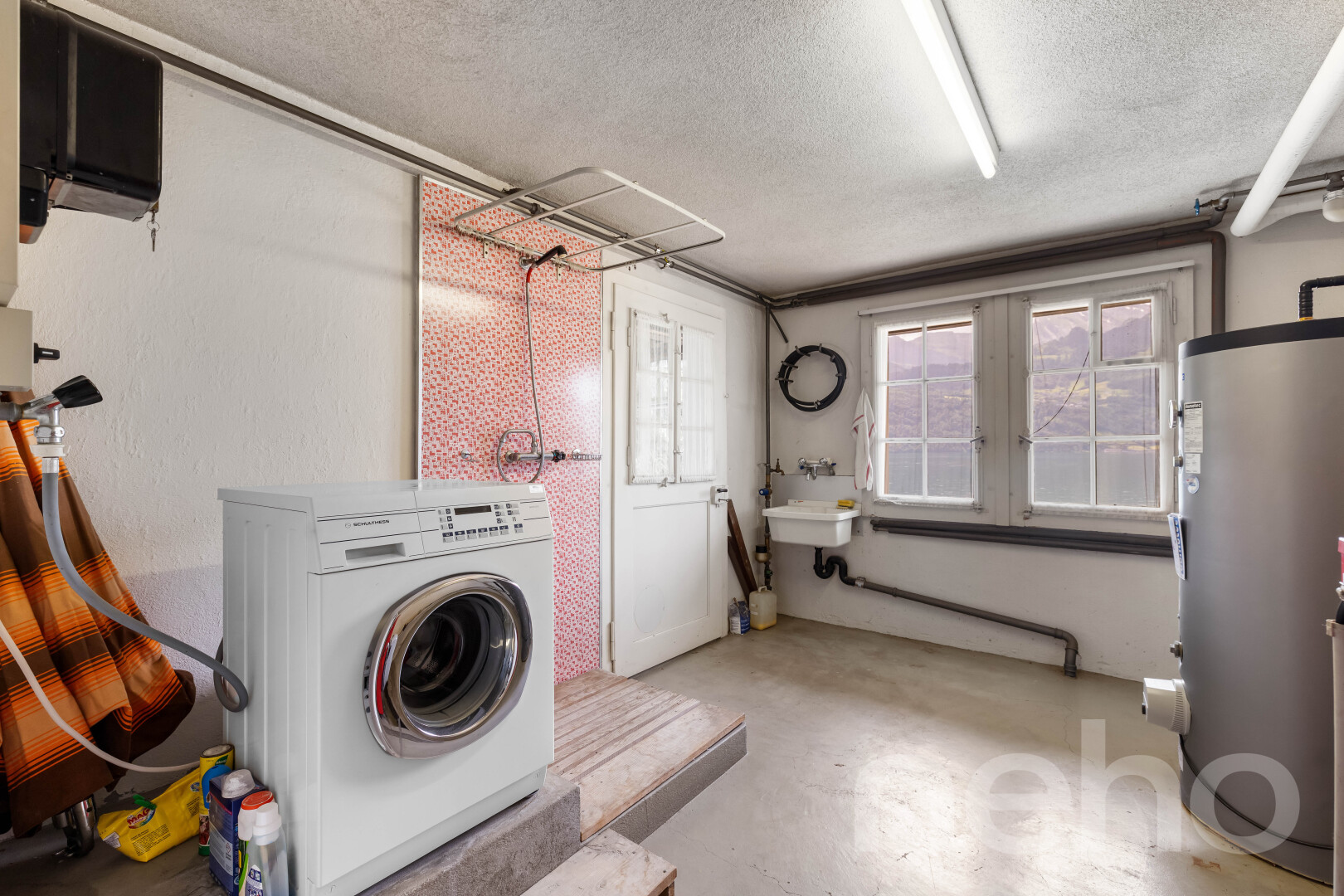 buanderie avec sol en béton, concrete floor, lave-linge et sèche-linge, chauffe-eau, et inside property