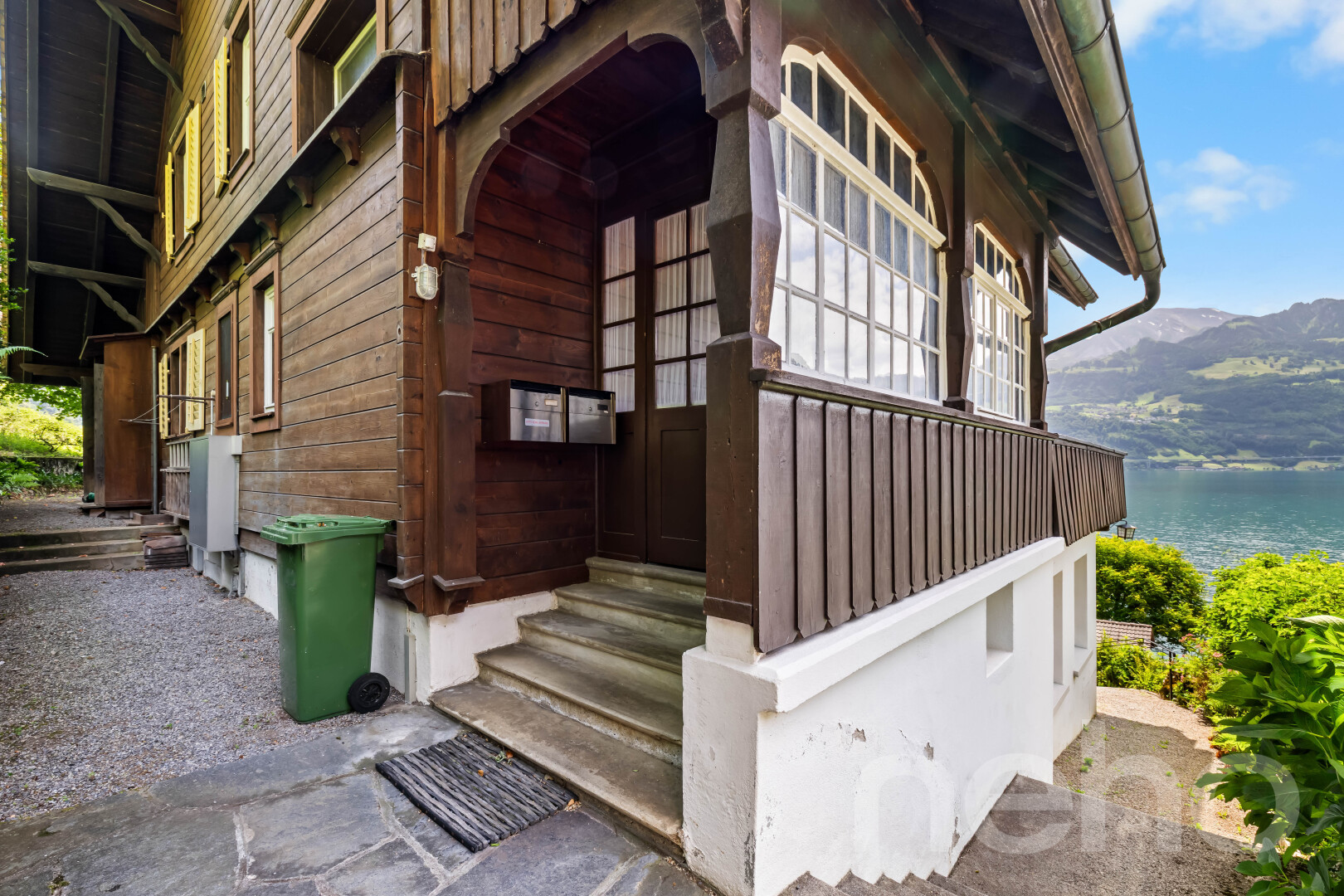 façade avec bardage en bois, fondation en béton, perron, marches d'entrée, et vue sur la montagne