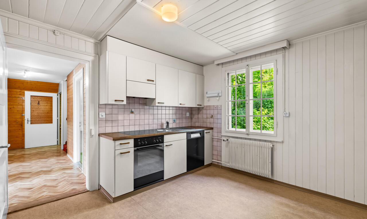 kitchen with wooden walls, white cabinets, black appliances, radiator, and wood counters