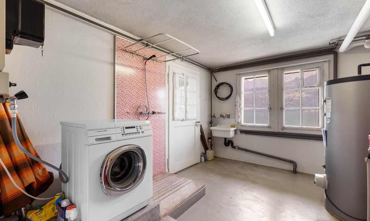 buanderie avec sol en béton, concrete floor, lave-linge et sèche-linge, chauffe-eau, et inside property