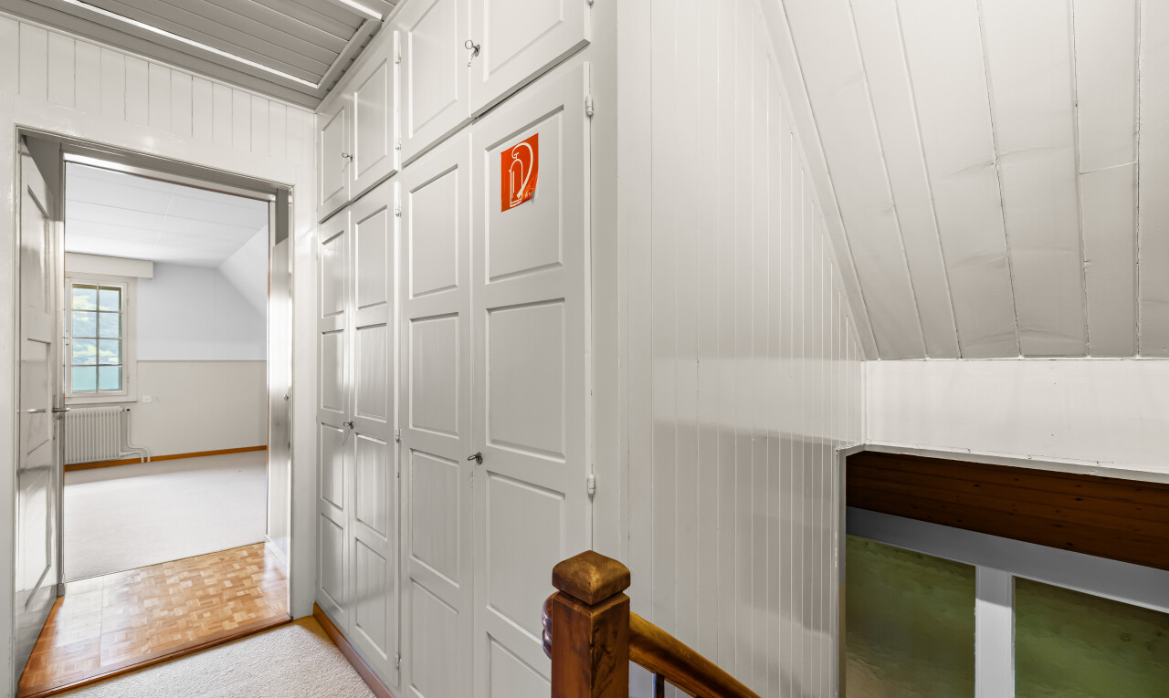 corridor featuring vaulted ceiling, light colored carpet, wooden walls, and radiator heating unit