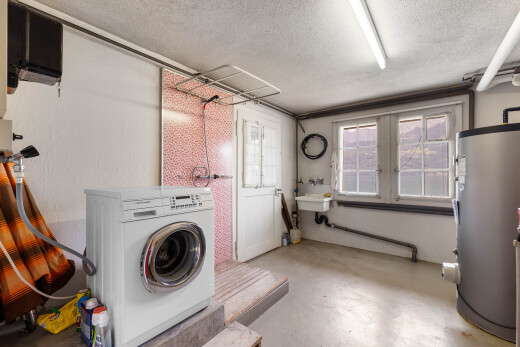 buanderie avec sol en béton, concrete floor, lave-linge et sèche-linge, chauffe-eau, et inside property