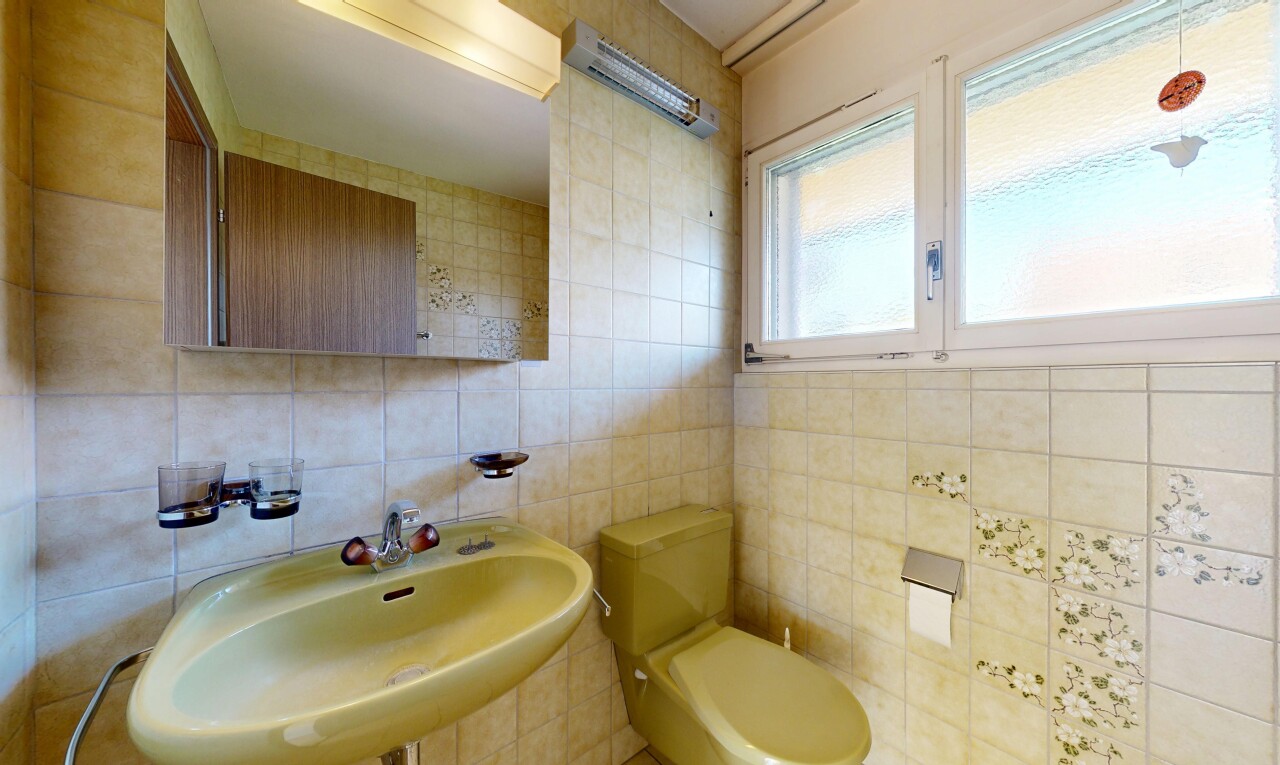 salle de bains avec toilette, miroir, évier, mur en carrelage, et tile wall