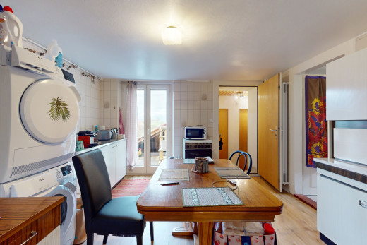 salle à manger avec lumière naturelle, machine à laver / sèche-linge superposés, mur carrelé, porte-fenêtre, et plancher de bois