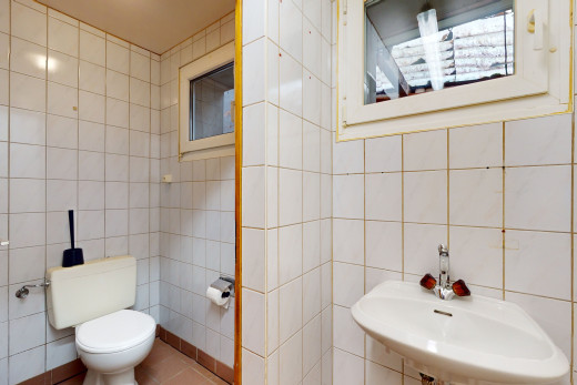 salle de bain avec vasque, lumière naturelle, toilettes, miroir, et mur carrelé