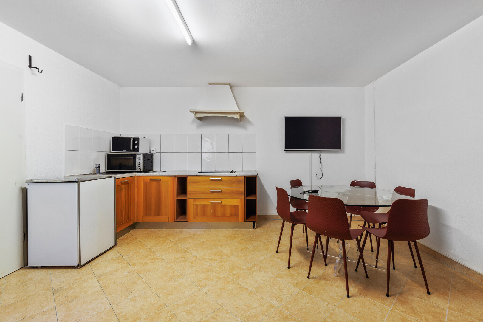 küche mit mittelbraune schränke, fernseher, drywall, gipskartonwand, und offene regale