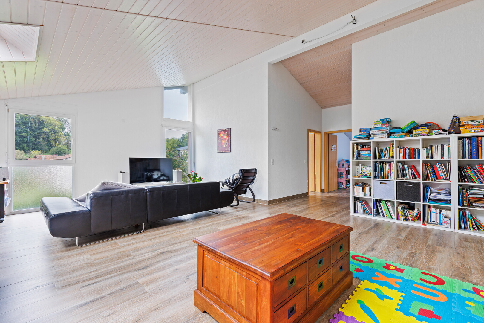 wohnzimmer mit vaulted ceiling, dachschräge, natural light, natürliches licht, und wood finish floor