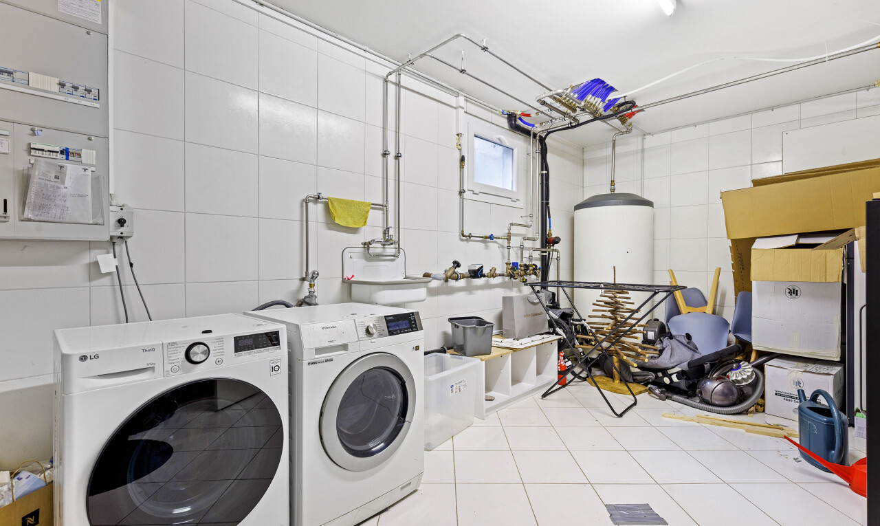 laundry area featuring light tile patterned flooring, gas water heater, washer and clothes dryer, and tile walls