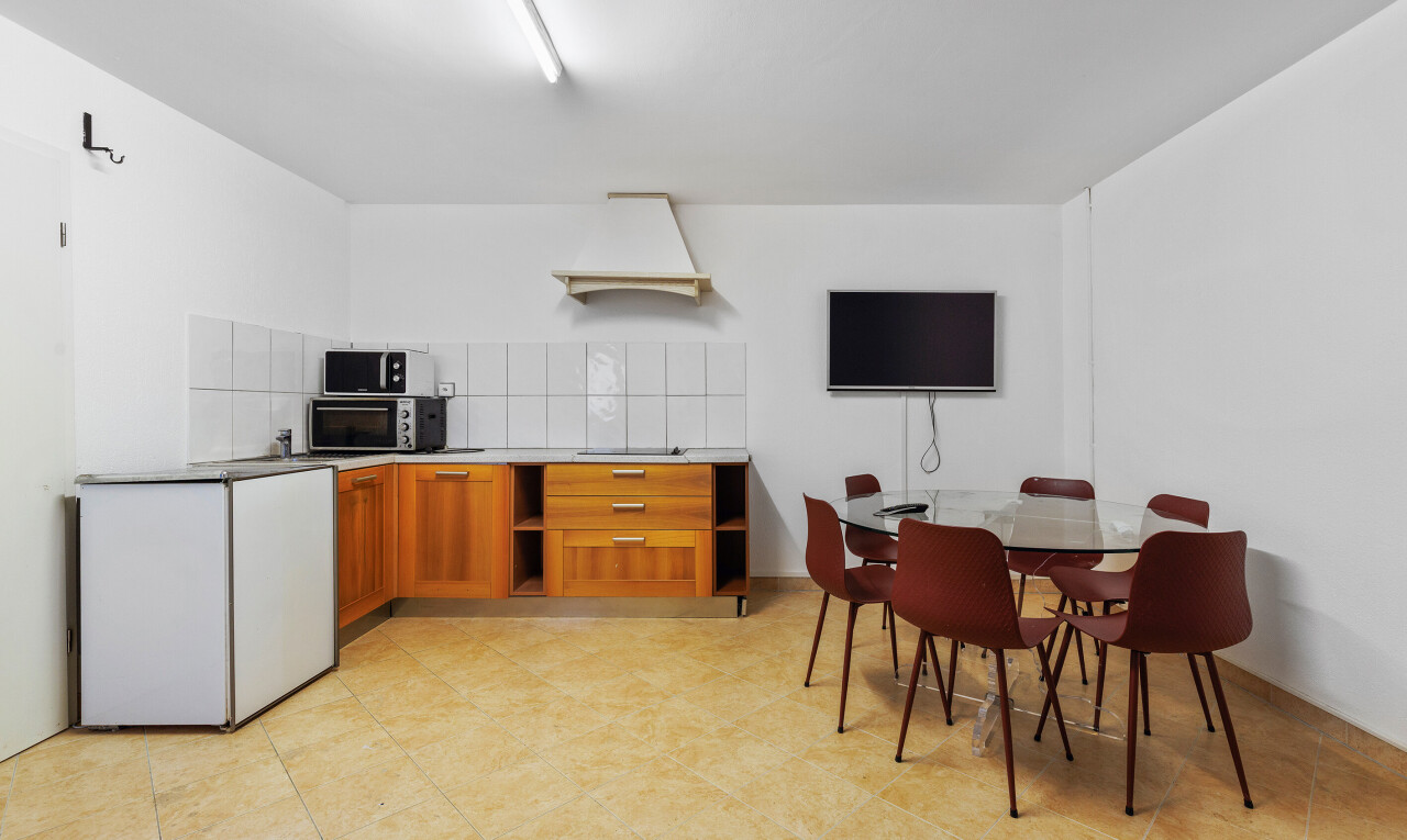 cuisine avec armoires marron moyen, télévision, drywall, cloison sèche, et étagères ouvertes