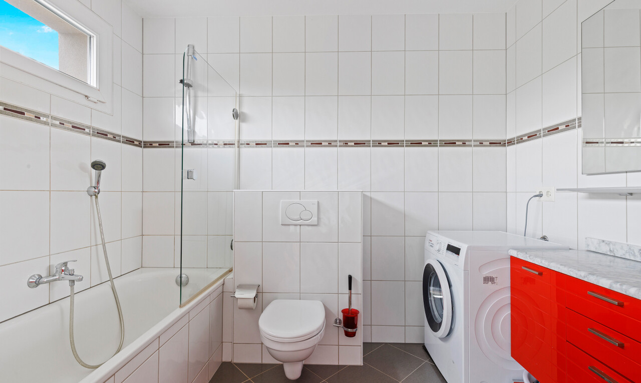 bathroom with tiled shower / bath combo, tile walls, dark tile patterned floors, and vanity
